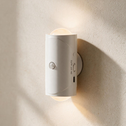 Close-up of a white Ambient Motion Wall Light showing its front motion sensor, side controls and warm light.