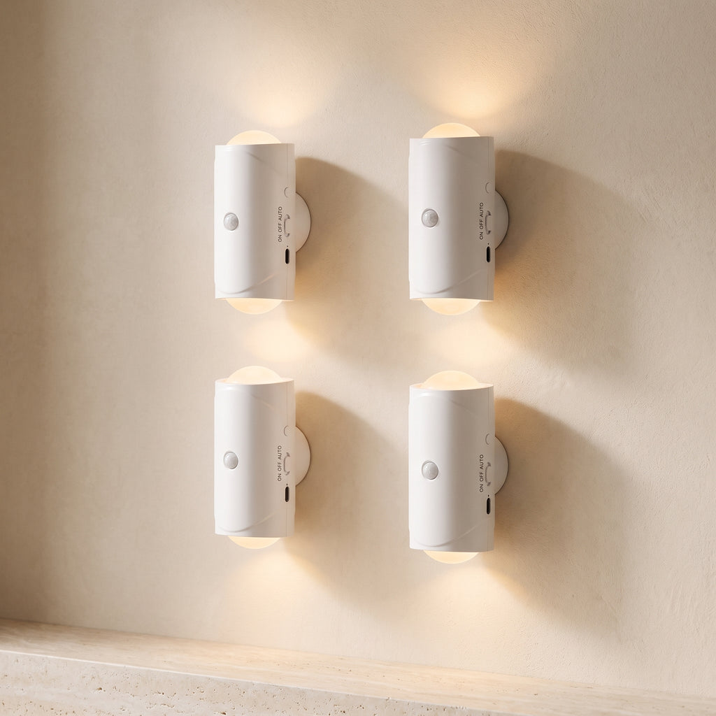 Four white Ambient Motion Wall Lights casting a warm glow on a sand-colored wall above a travertine ledge.
