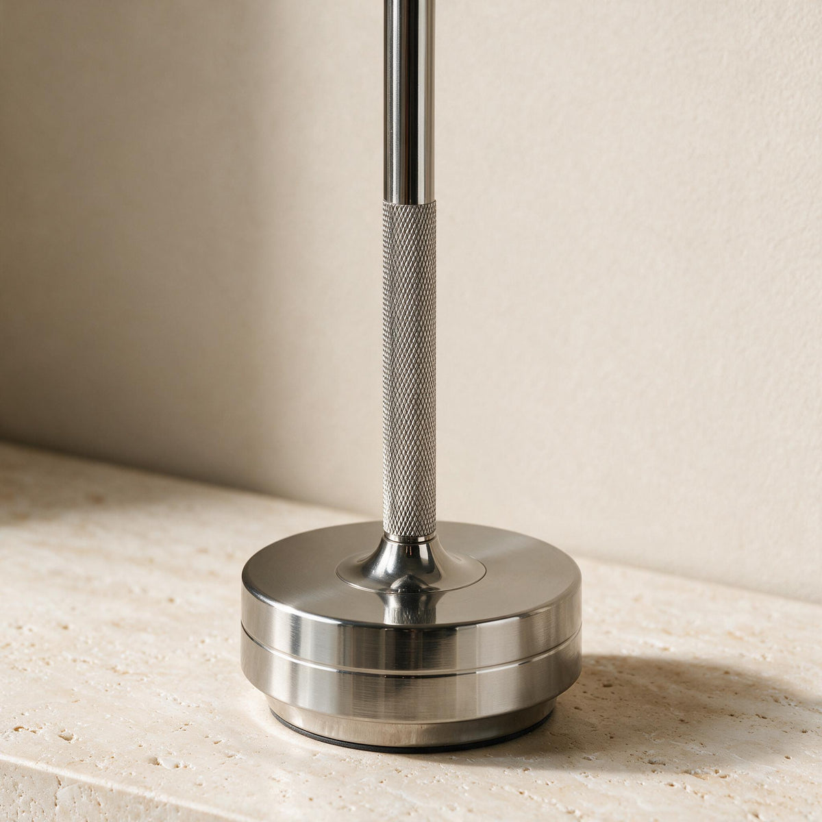 Close-up of a silver table lamp's diamond-textured stem and circular stepped base.