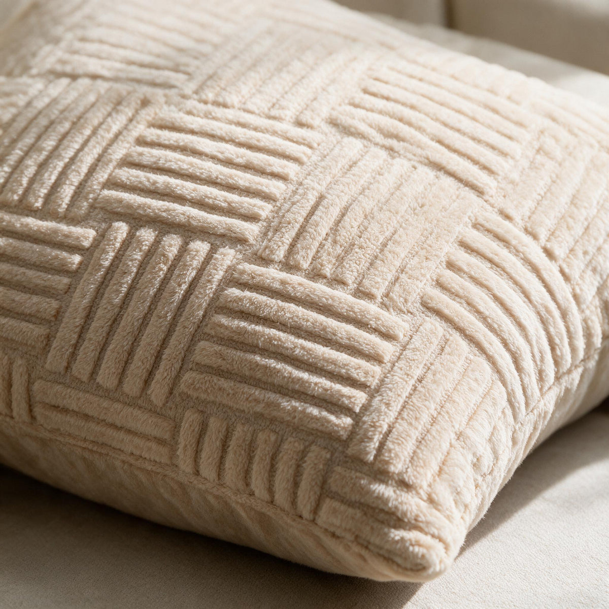Close-up of the raised geometric plush pattern and corner of a beige pillow cover.