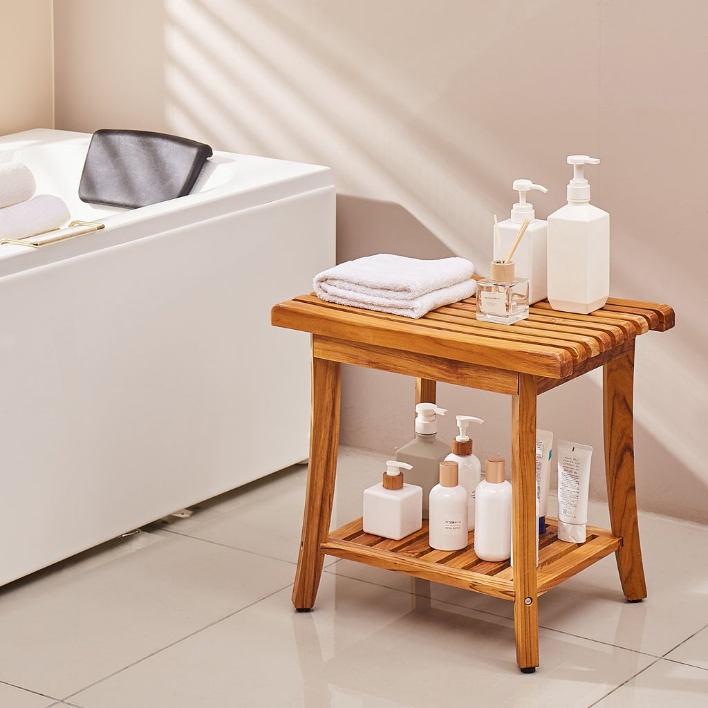Teak bench styled beside a bath; towels, bottles and bath not included